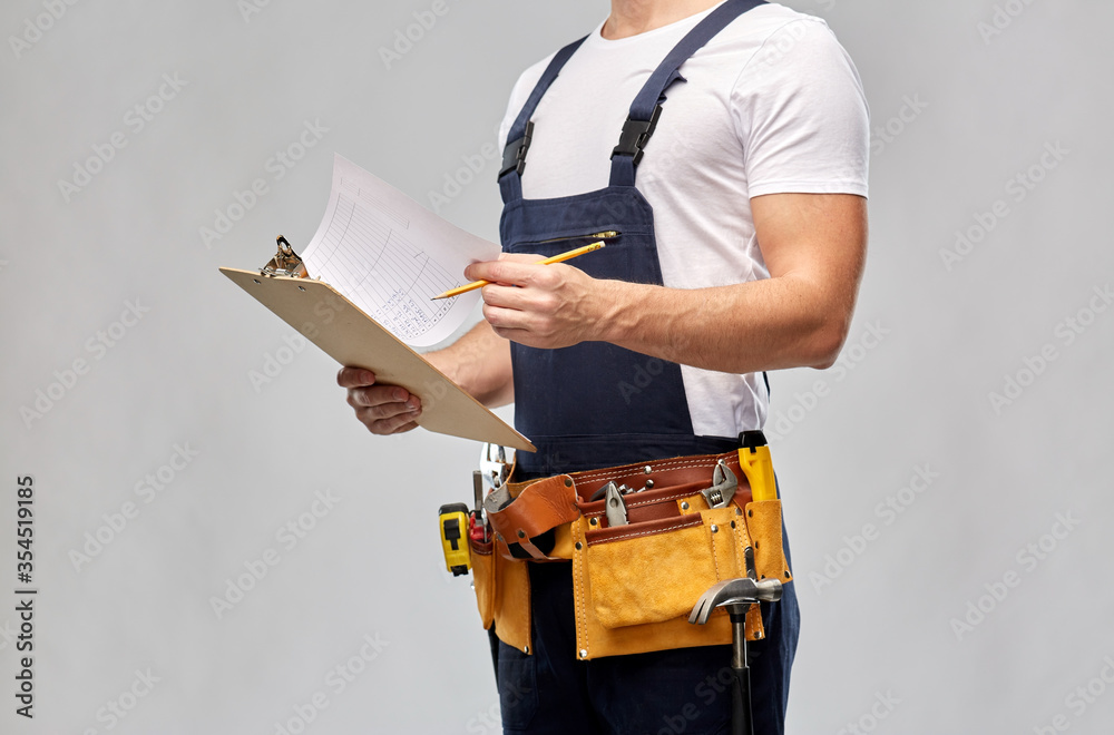 repair, construction and building - male worker or builder with clipboard, pencil and working tools on belt over grey background repair, construction and building - male worker or builder with clipboard, pencil and working tools on belt over grey background