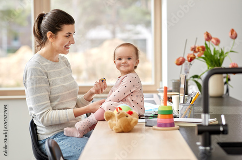 remote job, multi-tasking and family concept - happy smiling mother with baby working at home office