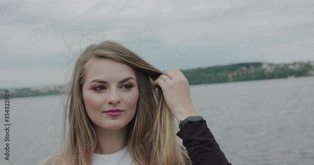 Charming girl with joyful face corrects her hair in the morning at seaside