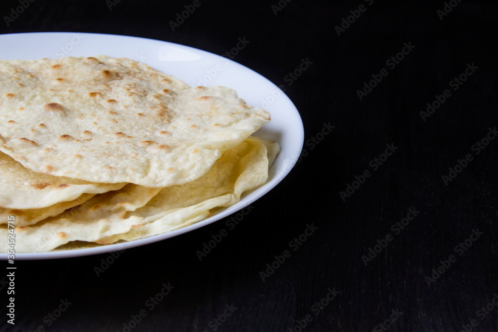 Delicious pita bread made at home in a pan. Thin pita bread on a white plate