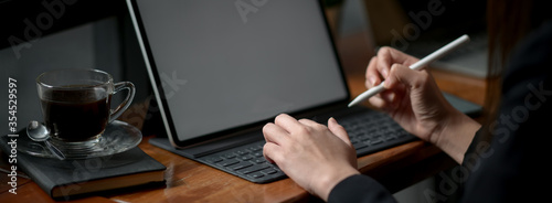 Businesswoman working on mock-up tablet with stylus pen and coffee cup on wooden counter bar photo