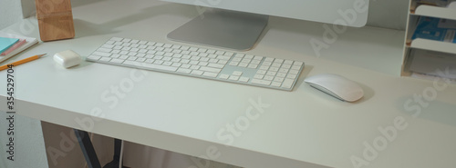 Minimal office desk with computer devices and office supplies on white table