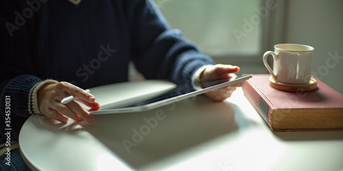 Cropped shot of a woman using digital tablet on white coffee table
