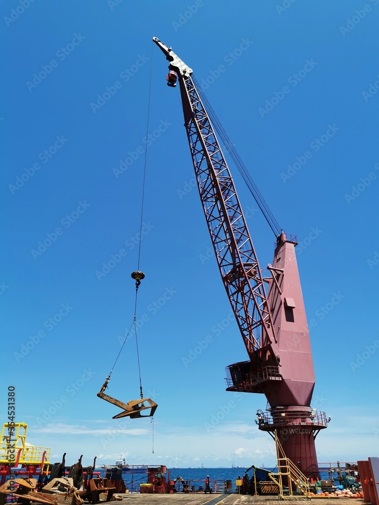 Offshore Vessel pedestal crane onboard barge lifting an anchor Stock