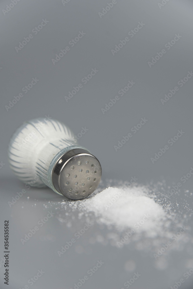 A pile of salt from salt shaker, concept excessive salt intake and white death A pile of salt from salt shaker, concept excessive salt intake and white death