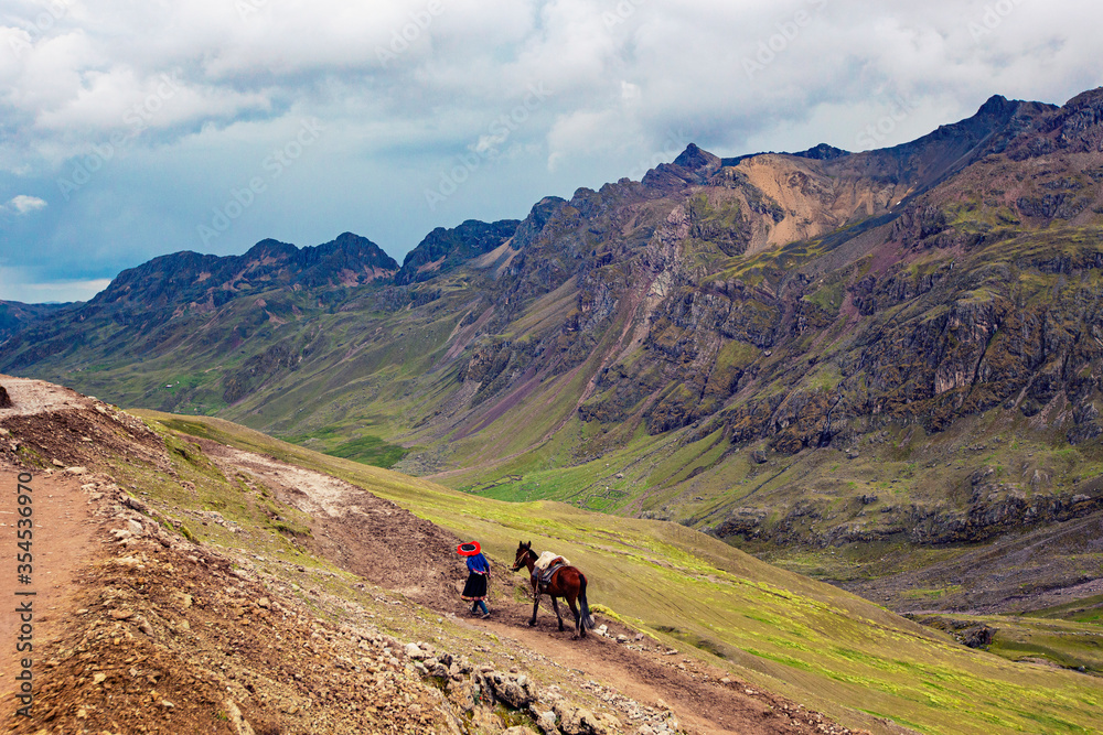 Mountain landscape in Peru. Peruvian woman with a horse near Vinicunca Rainbow mountain, Cusco province, Peru