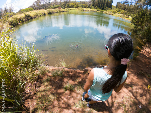 Girl feeding fish in a fish pond photo