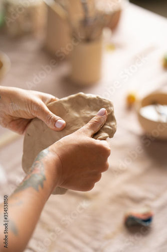 The potter's woman hands are shaped a cup from a clay. The process of creating pottery. The master ceramist works in his studio. Close-up, only hands. Crockery from clay own hands.