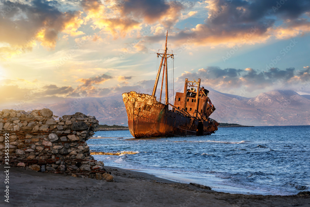 Blick auf ein altes Schiffswrack gestrandet am Strand bei Gythio, Peloponnes, Griechenland, bei Sonnenuntergang Blick auf ein altes Schiffswrack gestrandet am Strand bei Gythio, Peloponnes, Griechenland, bei Sonnenuntergang