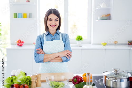 Portrait of her she nice attractive lovely cheerful housewife cooking lunch dinner dish snack culinary cookery stay home quarantine folded arms in modern light white interior kitchen house indoors
