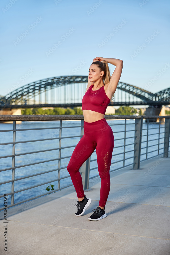 Fit in the city, young woman doing gymnastics and stretching exercises on the river early in the morning after sunrise Fit in the city, young woman doing gymnastics and stretching exercises on the river early in the morning after sunrise