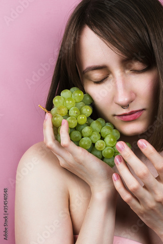 Young adult woman with her eyes closed holding grapes in her hands