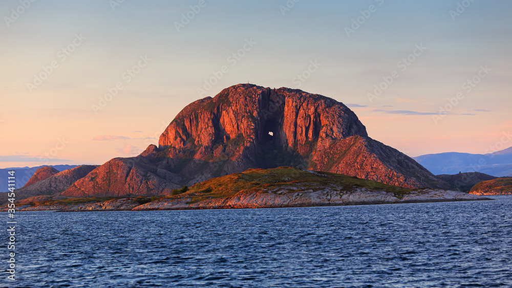 Torghatten mountain alone in the sea of Norway at sunset