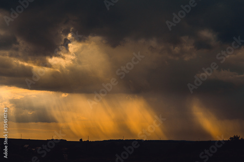 landscape with storm clouds and rain at sunset