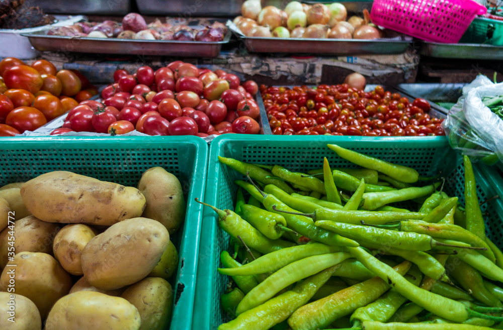 Potato, green chili pepper, tomato and onion in a basket shelf of local market in Thailand.