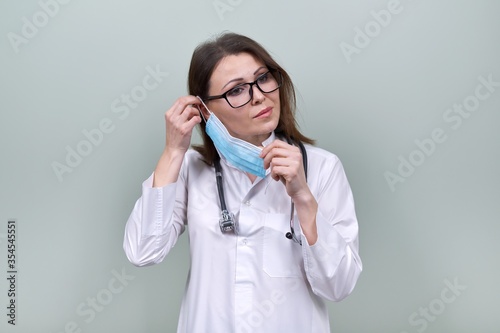 Woman doctor with stethoscope puts on medical protective mask