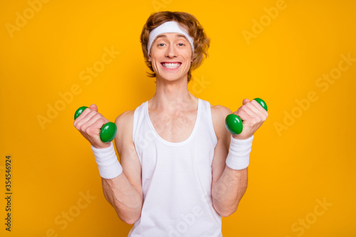 Close-up portrait of his he nice attractive funky glad cheerful cheery guy doing work out with small light dumbbell leisure isolated over bright vivid shine vibrant yellow color background