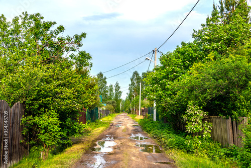 A typical street in the suburban areas in Russia with a dirt road