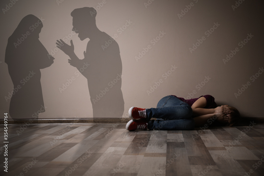 Φωτογραφία Little girl closing her eyes on floor indoors and silhouettes of arguing parents