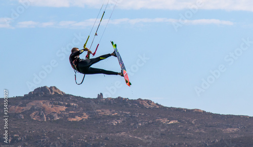 kite-boarder jumps high over hill