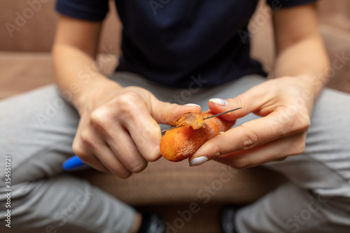 Girl peeling boiled carrots with a knife.
