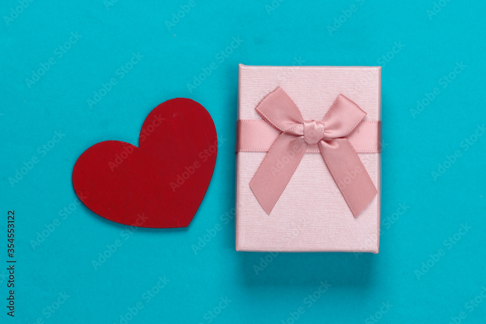 Gift box with bows and heart on blue background. Holiday, Valentine's Day. Top view. Minimalism