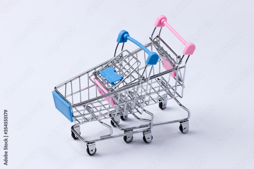 Two mini supermarket trolleys on a white background. Shopping concept.