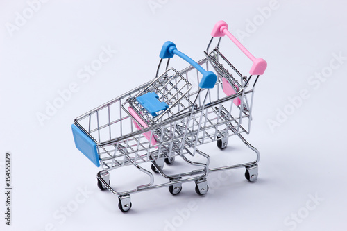 Two mini supermarket trolleys on a white background. Shopping concept.