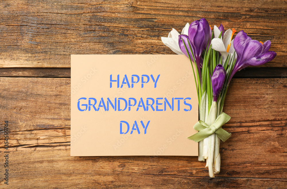 Beautiful spring crocus flowers and phrase HAPPY GRANDPARENTS DAY on wooden table, flat lay Beautiful spring crocus flowers and phrase HAPPY GRANDPARENTS DAY on wooden table, flat lay