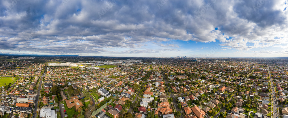 Fototapeta premium Aerial 180 degree view of the Melbourne suburb of Preston Victoria on a cloudy autumn day. The city of Melbourne can be seen in the distance.