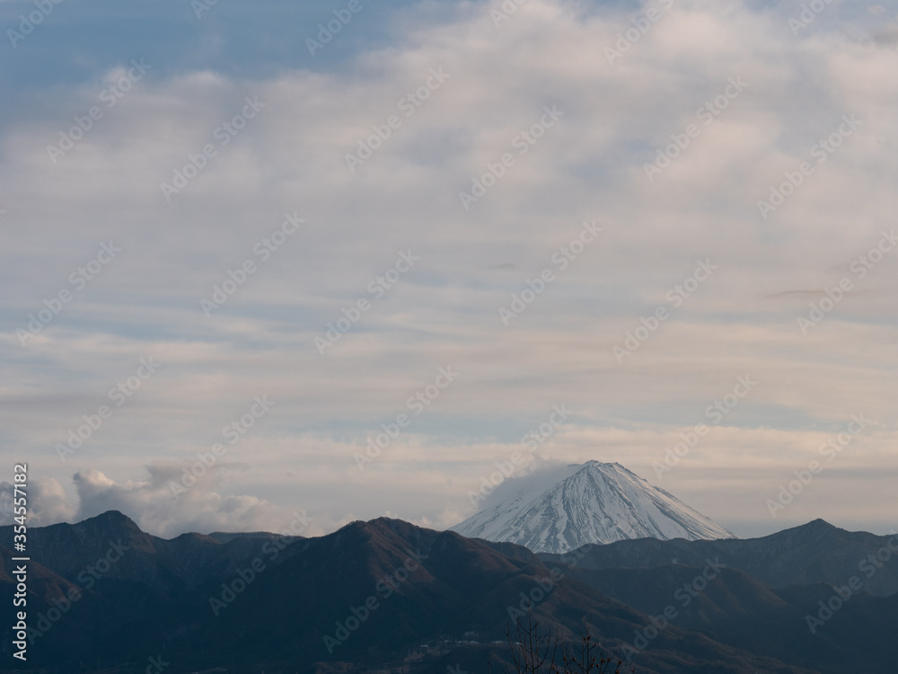 The tip of Mt. Fuji surrounded by clouds in the evening