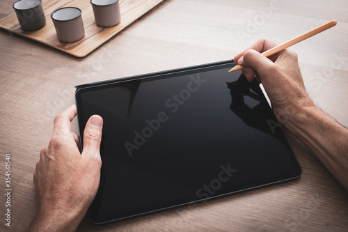 Konstfotografi Tablette tenue en main par un homme qui dessine avec un stylet sur un projet art