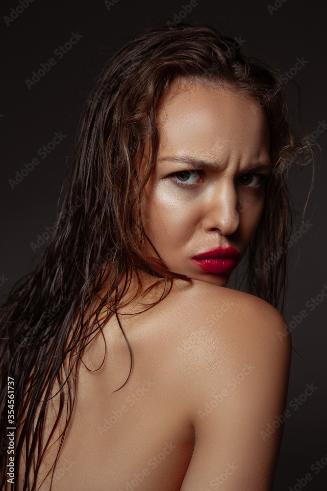 Feminine. Portrait of beautiful stylish woman isolated on dark studio background. Caucasian model with red lipstick, wet hair and shiny skin, bright make up. Beauty, fashion, emotions concept. Feminine. Portrait of beautiful stylish woman isolated on dark studio background. Caucasian model with red lipstick, wet hair and shiny skin, bright make up. Beauty, fashion, emotions concept.