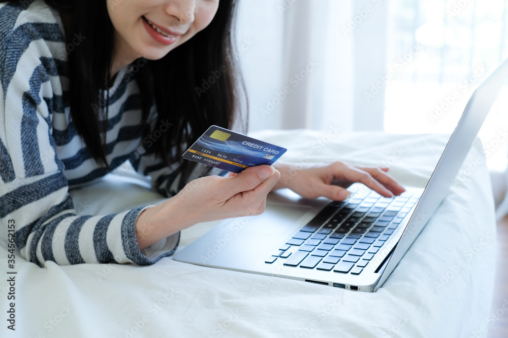 Asian woman using credit card and laptop for online shopping at bedroom. Asian woman using credit card and laptop for online shopping at bedroom.