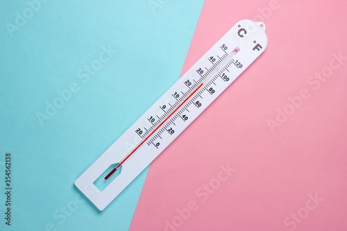 Weather thermometer on a blue-pink pastel background. Climate control. Top view photo
