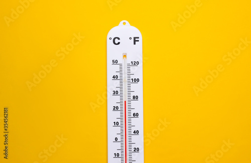 Weather thermometer on yellow background. Climate control. Top view photo