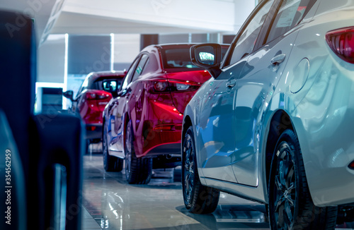 Rear view of new luxury red and white car parked in modern show room. Selective focus on white shiny car. Car dealership concept. Showroom interior. Automotive industry on coronavirus crisis concept.