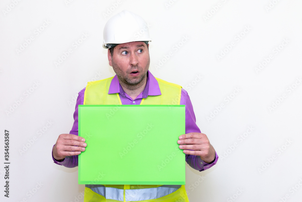 Portrait of curious surprised architect in a construction helmet holding a folder, free place mock up banner advertisement.Studio shoot. Portrait of curious surprised architect in a construction helmet holding a folder, free place mock up banner advertisement.Studio shoot.