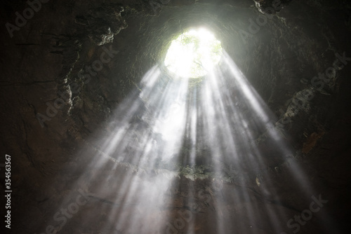 rays of light shine through at Jomblang cave near Yogyakarta, Indonesia