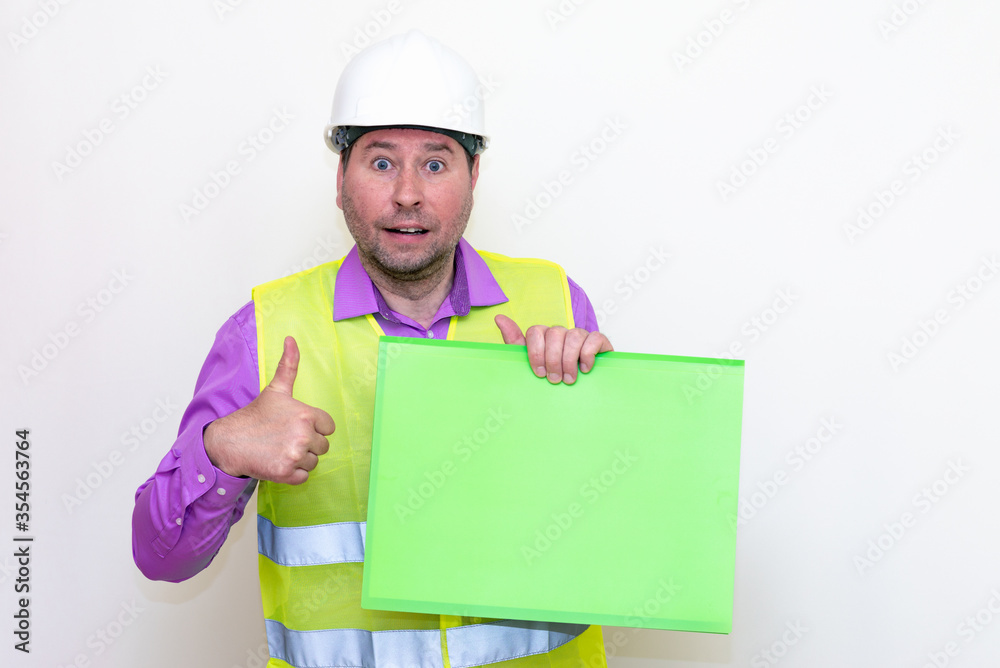 Portrait of curious surprised architect in a construction helmet holding a folder, free place mock up banner advertisement.Studio shoot. Portrait of curious surprised architect in a construction helmet holding a folder, free place mock up banner advertisement.Studio shoot.