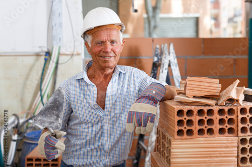 Foto Happy bricklayer near brick stack