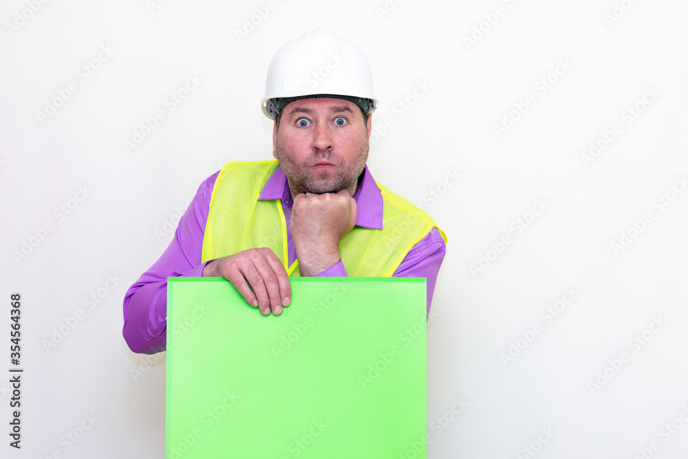 Portrait of curious surprised architect in a construction helmet holding a folder, free place mock up banner advertisement.Studio shoot. Portrait of curious surprised architect in a construction helmet holding a folder, free place mock up banner advertisement.Studio shoot.