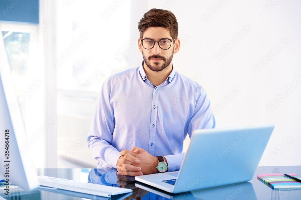 Young businessman with his laptop sitting at office desk Young businessman with his laptop sitting at office desk