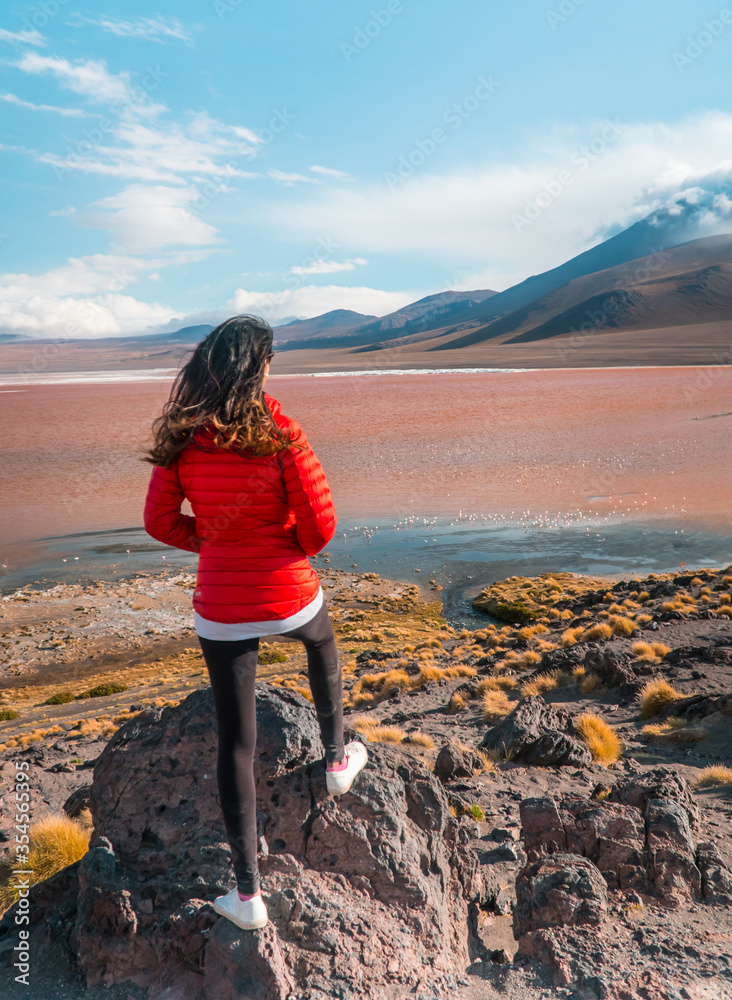 Fototapeta premium Tourist, Red Lake mountain landscape, Bolivia. Woman with Beautiful colored water, with mountains background and unique scenic view. Flamingos in the lake. Shot in Uyuni, Salar de Uyuni, South America