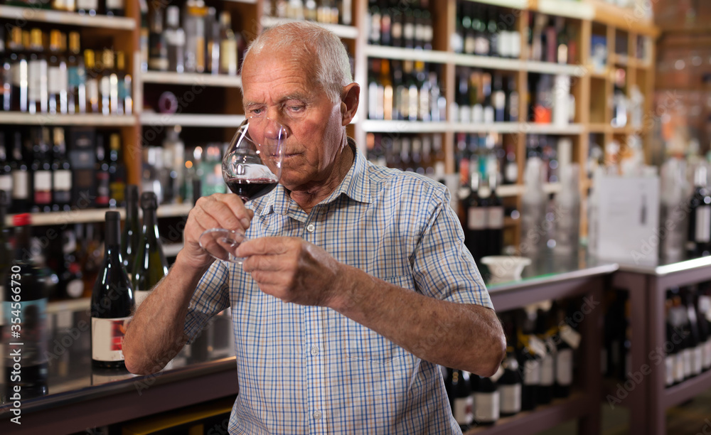 Mature man inspecting quality of red wine