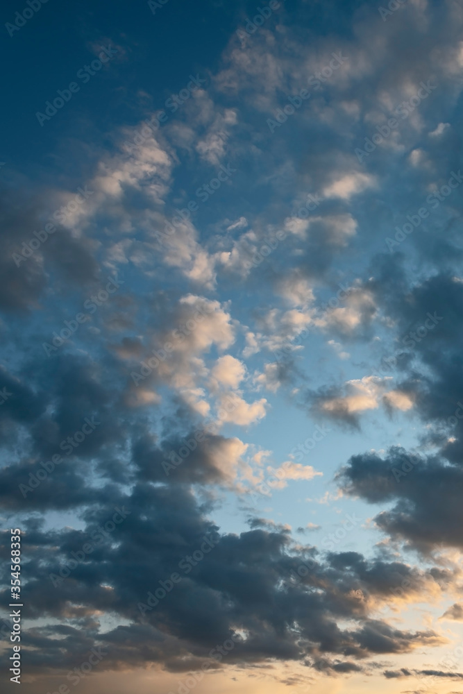 Naklejka premium sun sets behind the clouds in the blue evening sky as a natural background