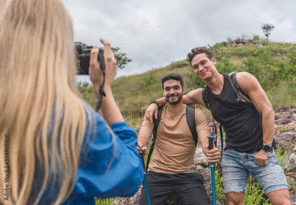 Naklejka premium Woman taking a photo of two hiker man between a vacation mountain journey
