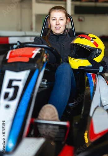 girl posing with helmet in her hands at kart circuit