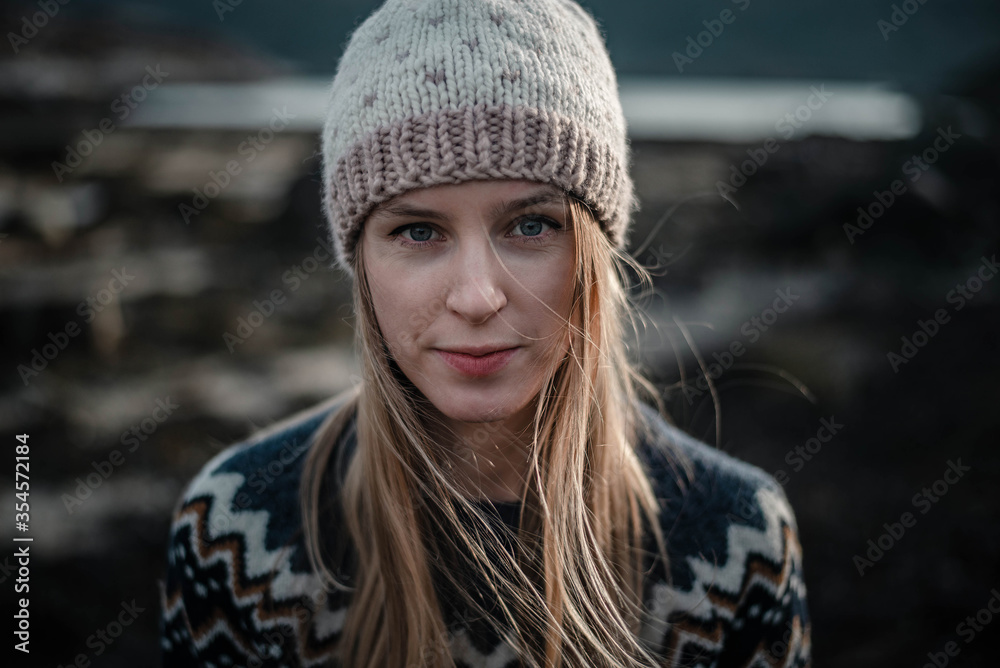 Portrait of a young woman posing in handmade knitted hat. Natural blonde haired woman looking to a camera Portrait of a young woman posing in handmade knitted hat. Natural blonde haired woman looking to a camera