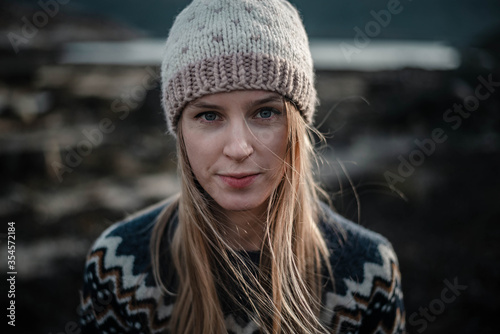 Portrait of a young woman posing in handmade knitted hat. Natural blonde haired woman looking to a camera